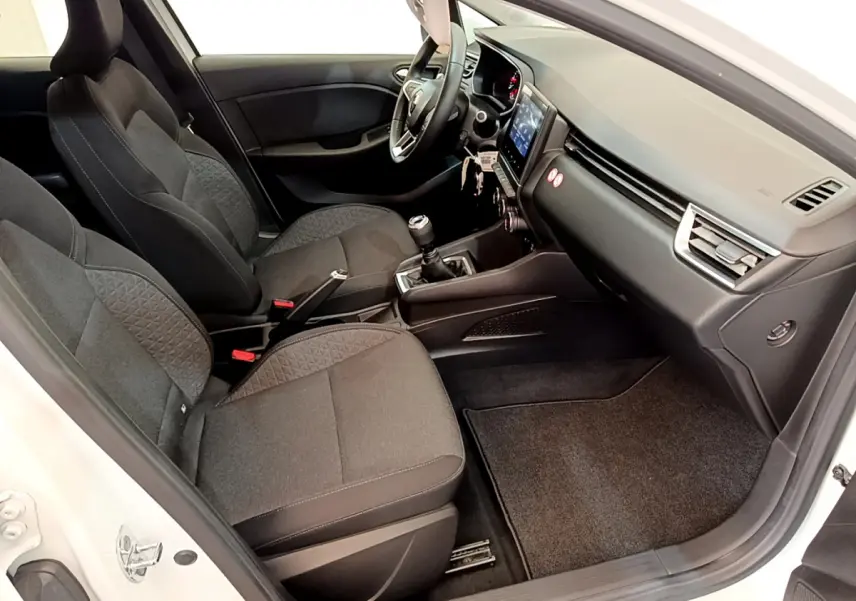 Vue intérieure côté conducteur de la Renault Clio Business blanche, montrant sièges noirs et tableau de bord avec écran tactile.