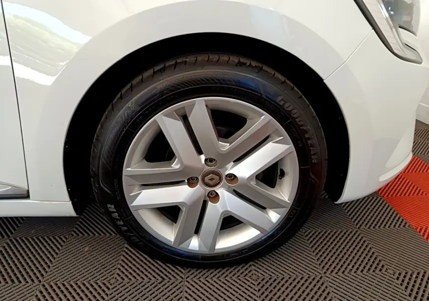 Gros plan sur la roue avant gauche d'une Renault Clio Business blanche, jante alliage et pneu Goodyear visible.