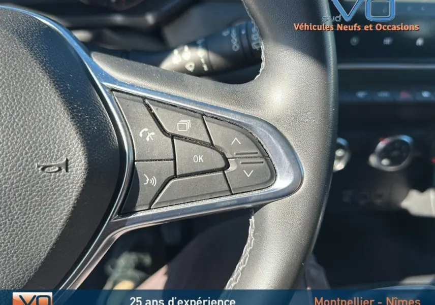 Gros plan sur les commandes au volant du Renault Captur gris, version TCe 90 Business, avec tableau de bord en arrière-plan.