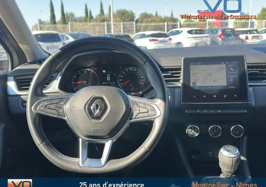 Vue intérieure du tableau de bord et volant du Renault Captur gris TCe 90 21 Business avec boîte manuelle et écran tactile central.