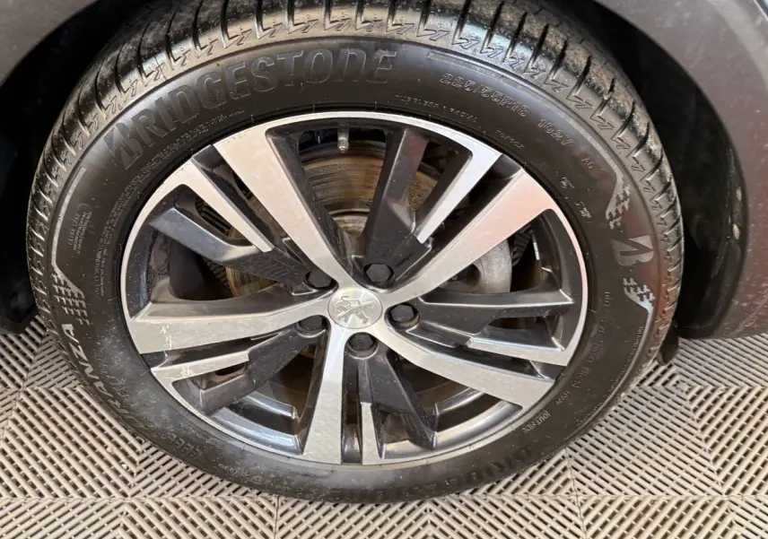 Gros plan sur la jante alliage bicolore et pneu Bridgestone du côté avant droit du Peugeot 5008 bleu.