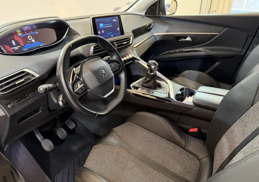 Vue intérieure côté conducteur du Peugeot 5008 avec volant cuir multifonctions et levier de vitesse manuel.