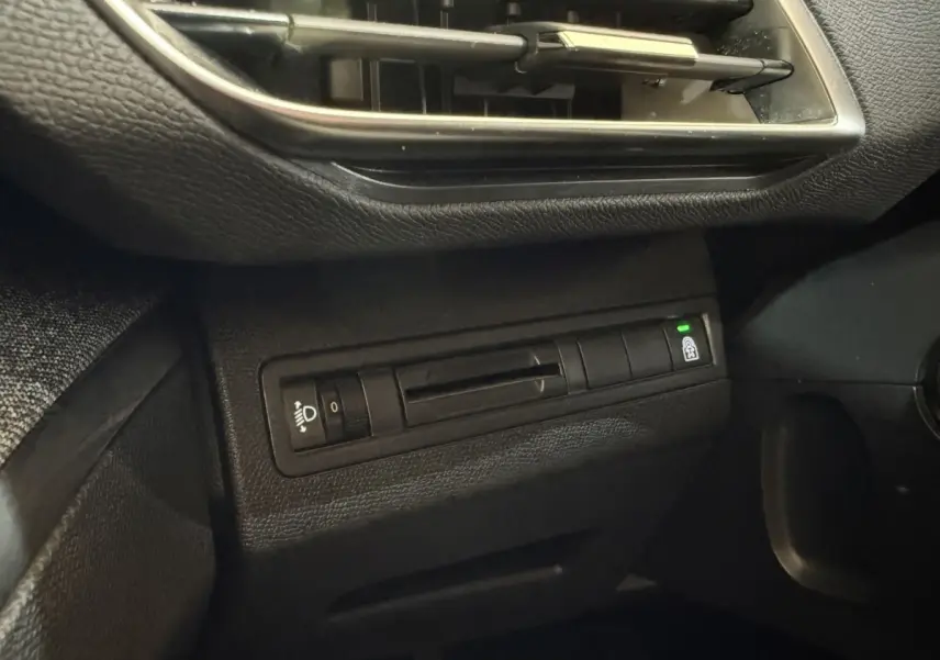 Détail du tableau de bord noir du Peugeot 5008 2019 avec commande réglage phares et bouton verrouillage portes.