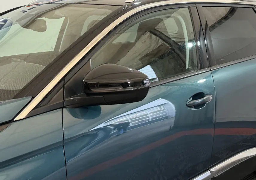 Vue côté gauche rapprochée du Peugeot 5008 bleu avec rétroviseur noir brillant et contours chromés.