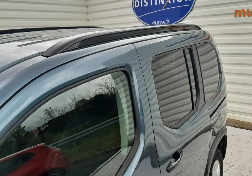 Vue latérale droite du Peugeot Rifter bleu Kiama 2026, mettant en valeur les vitres teintées et la barre de toit noire.