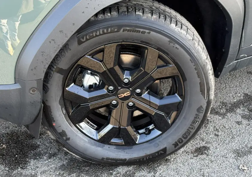 Gros plan sur la jante alliage noire 17 pouces du Dacia Duster kaki, avec pneu Hankook visible côté avant droit.