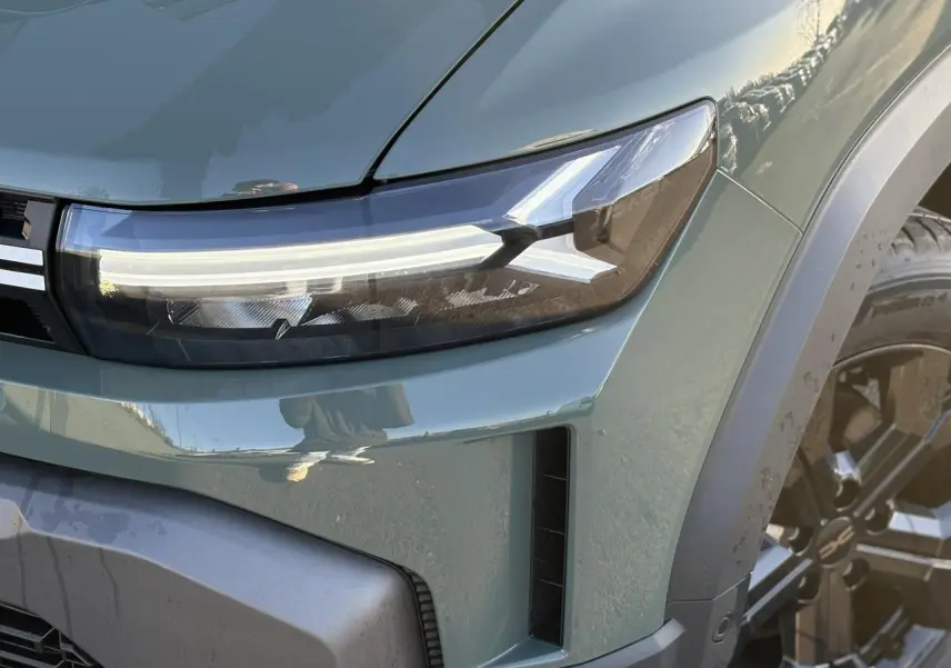 Gros plan sur le phare avant droit du Dacia Duster 2026 kaki lichen avec jante alliage noire et signature lumineuse LED.