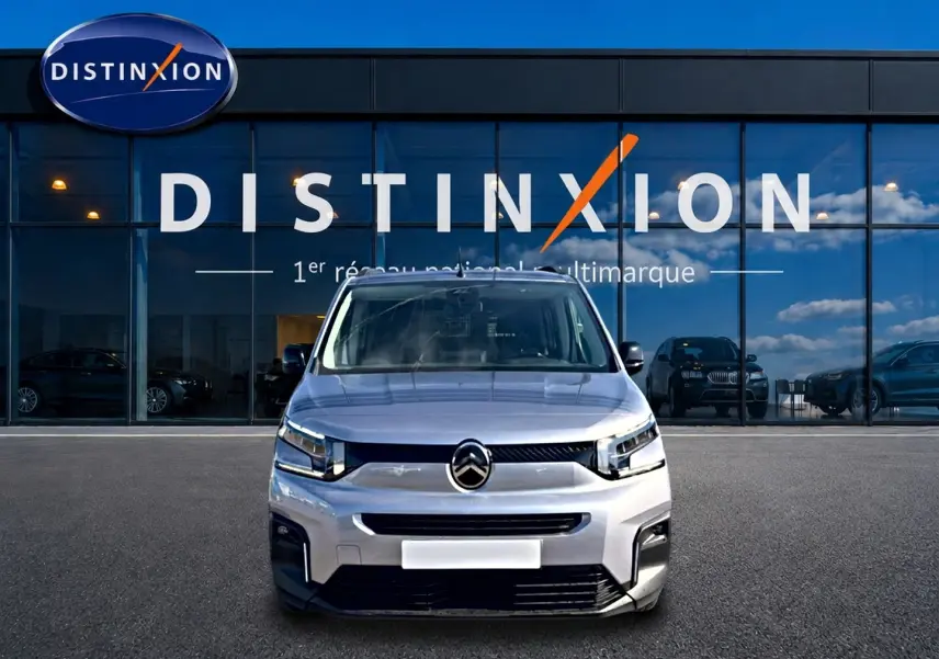 Vue avant d'un Citroën Berlingo 2026 gris acier, avec calandre noire et phares LED devant un showroom Distinxion.