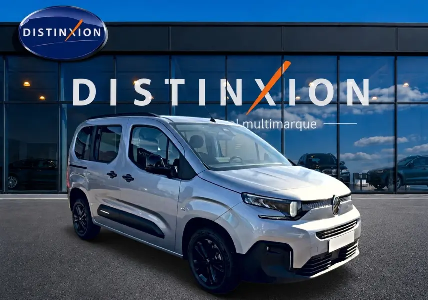 Vue 3/4 avant droite du Citroën Berlingo Steel Grey 2026 avec barres de toit et jantes noires devant un showroom Distinxion.