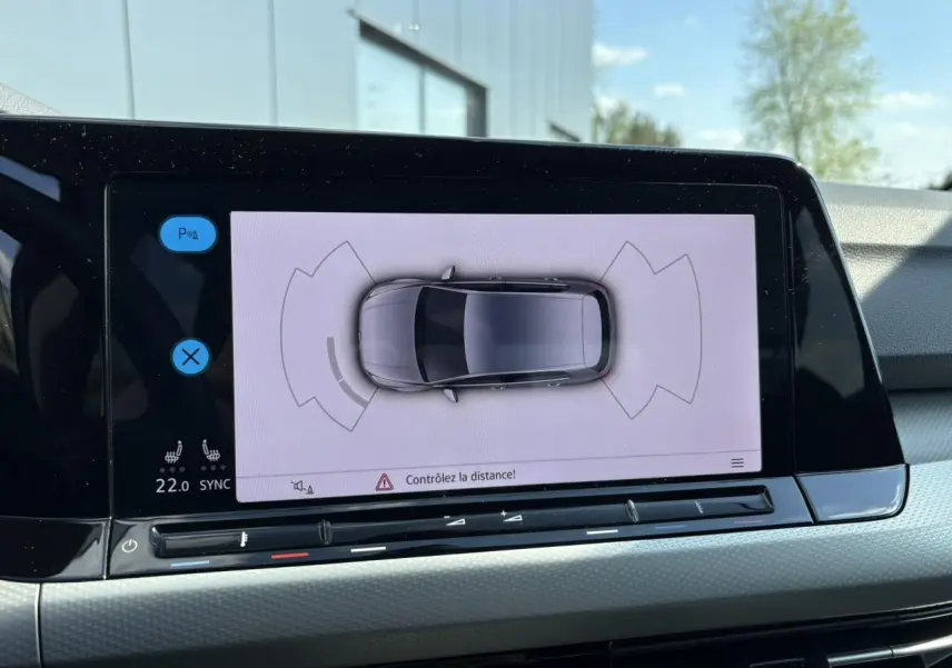 Écran tactile intérieur affichant la vue aérienne de la Volkswagen Golf VIII gris lunaire avec capteurs de stationnement actifs.