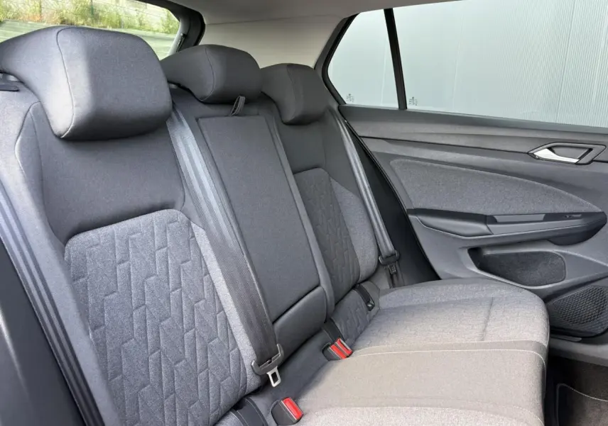 Vue latérale droite de la banquette arrière grise de la Volkswagen Golf VIII 1.5 TSI 2024 avec ceintures et appuie-têtes.