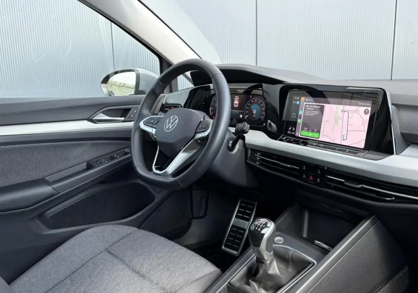 Intérieur de la Volkswagen Golf VIII essence 2024, vue côté conducteur, volant cuir multifonction et écran tactile navigation.