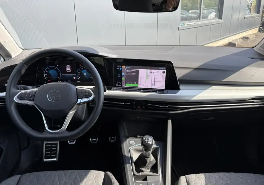 Vue intérieure de la Volkswagen Golf VIII 1.5 TSI 2024 montrant le volant multifonction, tableau de bord numérique et levier de vitesses manuel.