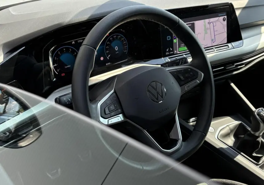 Vue rapprochée de l'intérieur de la Volkswagen Golf VIII 1.5 TSI 2024, volant cuir multifonction et écran tactile.