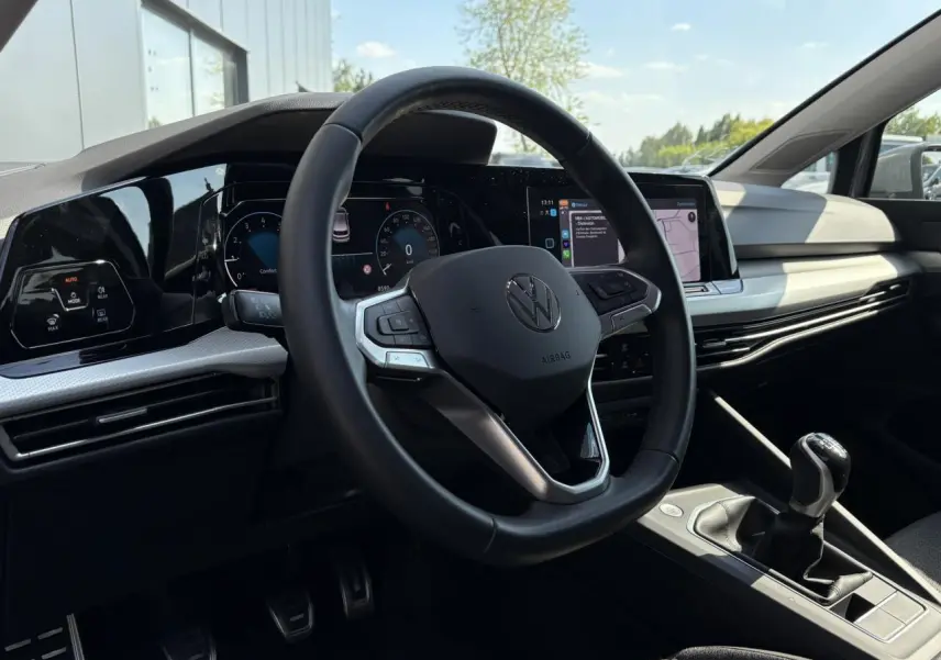 Vue intérieure de la Volkswagen Golf VIII 1.5 TSI 2024, volant cuir multifonction et levier de vitesse manuel visibles.