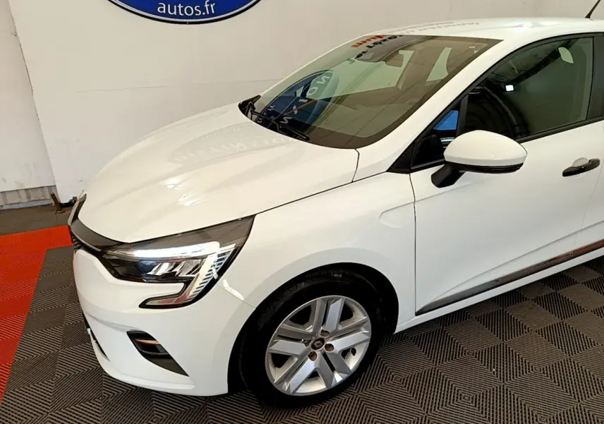 Vue 3/4 avant droit d'une Renault Clio Business blanche avec phares LED et jantes alliage visibles.