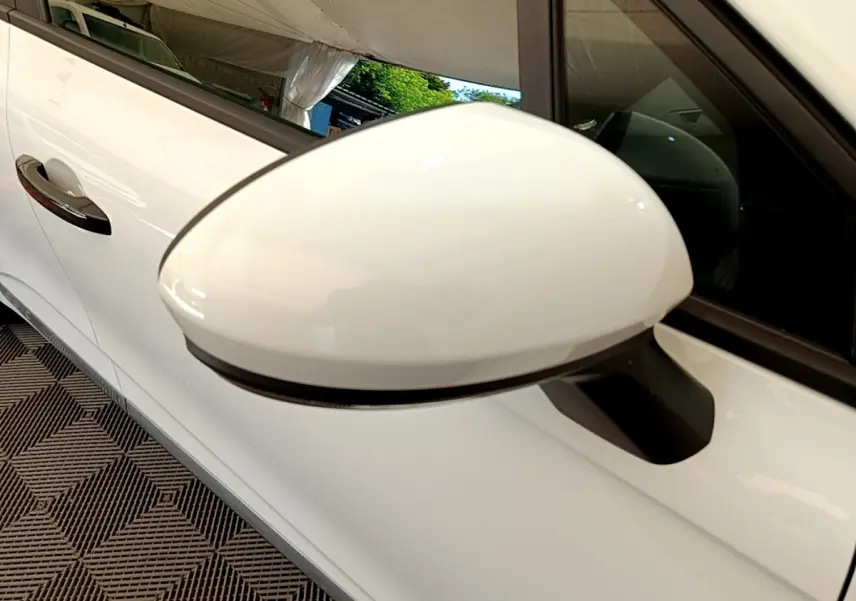 Gros plan sur le rétroviseur droit blanc d'une Renault Clio Business 2021, avec porte et vitre latérale visibles.