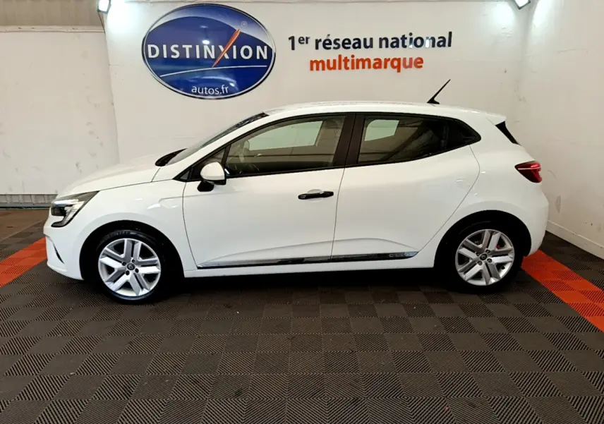 Profil droit d'une Renault Clio Business blanche 2021, avec jantes alliage et poignées noires contrastantes dans un showroom.