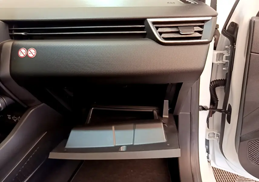 Intérieur de la Renault Clio Business blanche 2021, vue côté passager avec boîte à gants ouverte et tableau de bord noir.