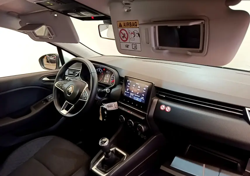 Vue intérieure côté conducteur de la Renault Clio Business blanche 2021, volant cuir et écran tactile central visible.