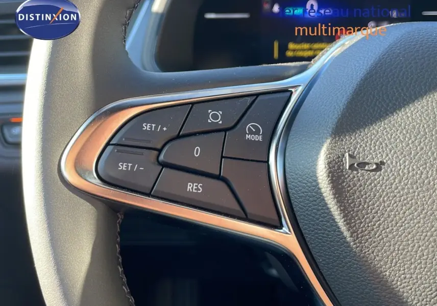 Gros plan sur les commandes au volant du Renault Captur E-Tech gris rafale, mettant en valeur les boutons de régulateur de vitesse.