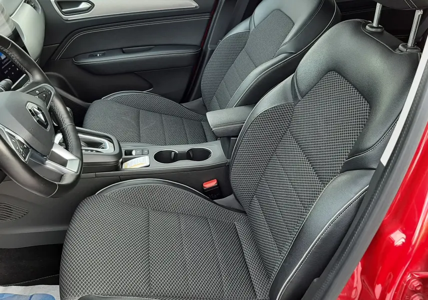 Vue intérieure côté conducteur de la Renault Arkana rouge Flame, sièges avant en tissu noir avec surpiqûres blanches.