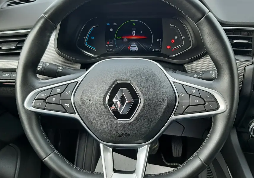 Vue centrée sur le volant noir du Renault Arkana 1.6 E-TECH 145 Intens avec tableau de bord numérique allumé.