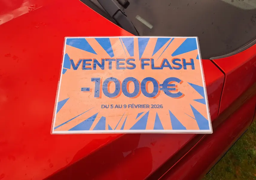 Vue rapprochée du capot rouge flame d'une Renault Arkana 2021 avec une affiche de promotion "Ventes Flash -1000€".