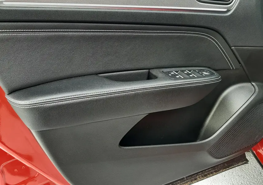 Vue rapprochée de la porte avant gauche rouge flame d’une Renault Arkana 1.6 E-TECH 145 Intens avec garniture intérieure noire.