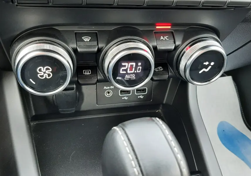 Gros plan sur la console centrale de la Renault Arkana rouge Flame, montrant les commandes de climatisation et la boîte automatique.