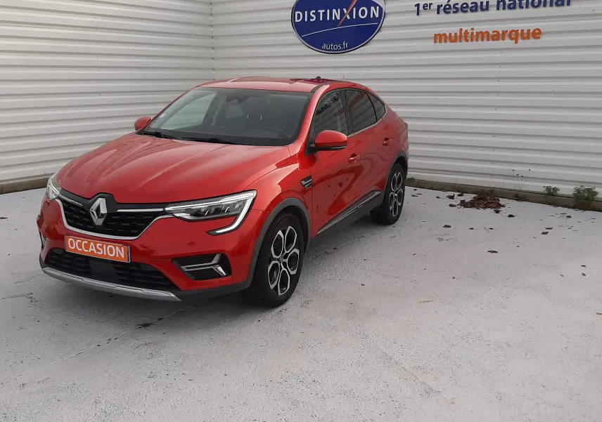 Renault Arkana rouge Flame en 3/4 avant droit, stationné devant un mur blanc avec logo Distinxion.