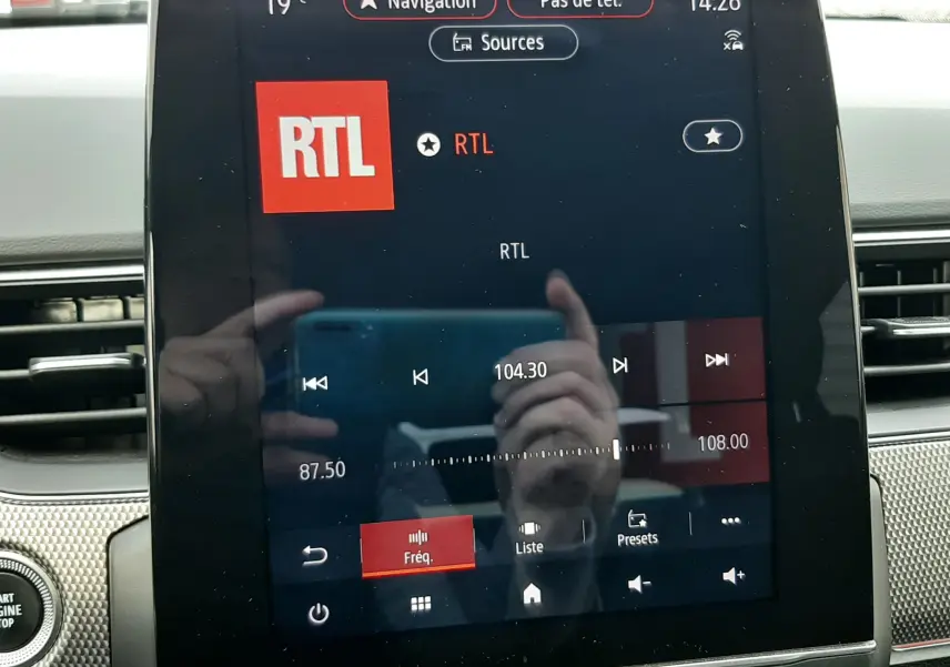 Vue rapprochée de l’écran tactile central du Renault Arkana rouge Flame, affichant la radio RTL à 104.3 FM.