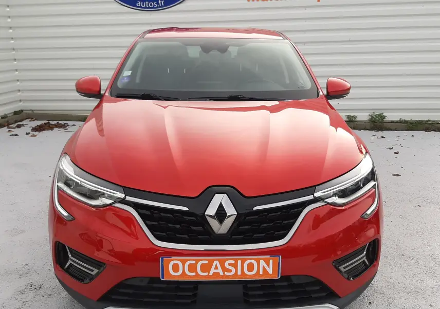 Vue frontale d'un Renault Arkana rouge flamme avec calandre noire et plaque "OCCASION" visible.