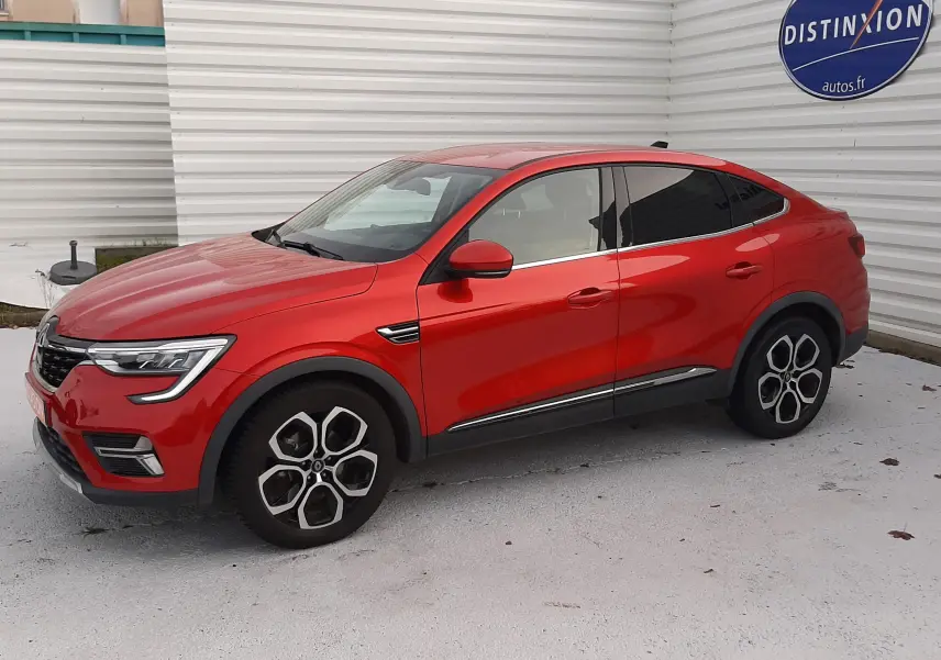 Renault Arkana 1.6 E-TECH rouge Flame en vue 3/4 avant côté gauche, avec jantes alliage distinctives et carrosserie lisse.