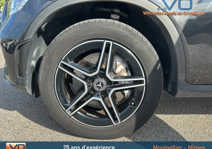 Gros plan sur la jante alliage noire à cinq branches du Mercedes GLC 300 de gris anthracite, version AMG Line.