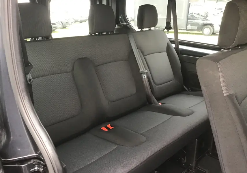 Vue intérieure côté gauche du siège arrière gris foncé du Renault Trafic Combi L2 2.0 DCI 150 Energy 9 places, tissu et ceintures visibles.
