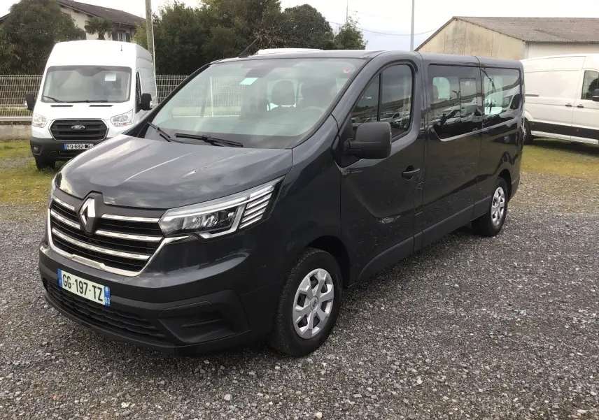 Vue 3/4 avant droit d’un Renault Trafic Combi gris comète 2022, avec calandre chromée et jantes acier.