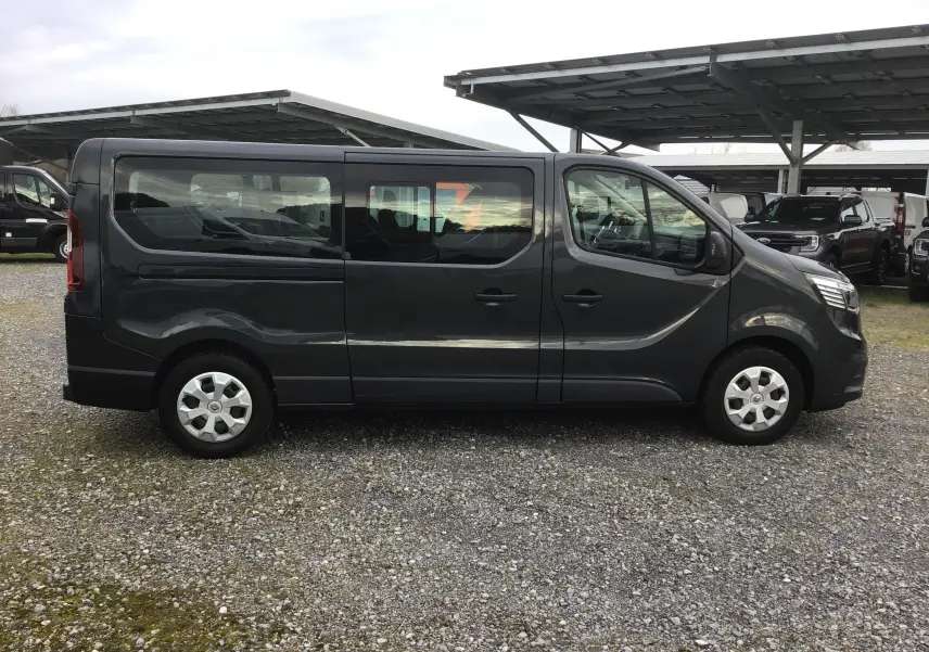 Vue de profil côté gauche d’un Renault Trafic Combi gris comète 2022, grand fourgon avec vitres latérales et jantes acier.