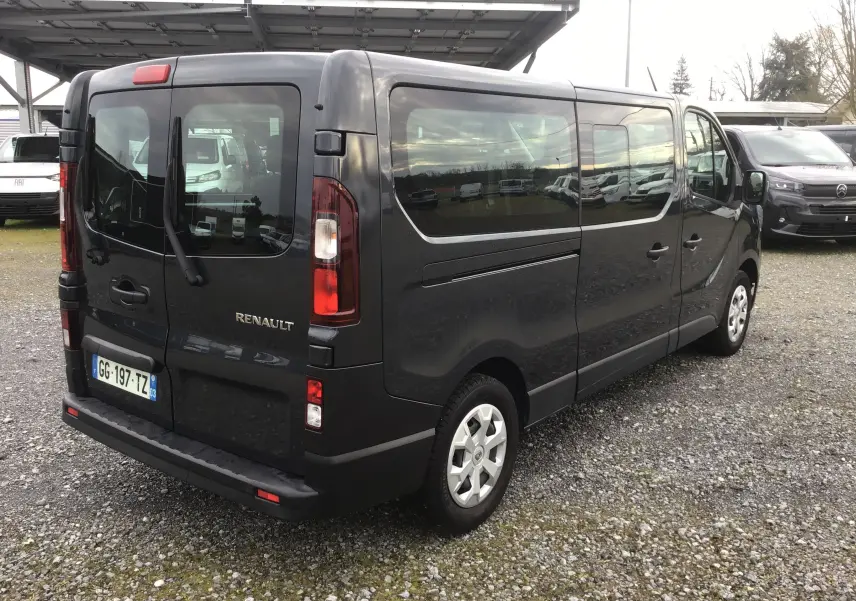 Vue 3/4 arrière droite d’un Renault Trafic Combi gris comète avec vitres latérales teintées et portes arrière battantes.