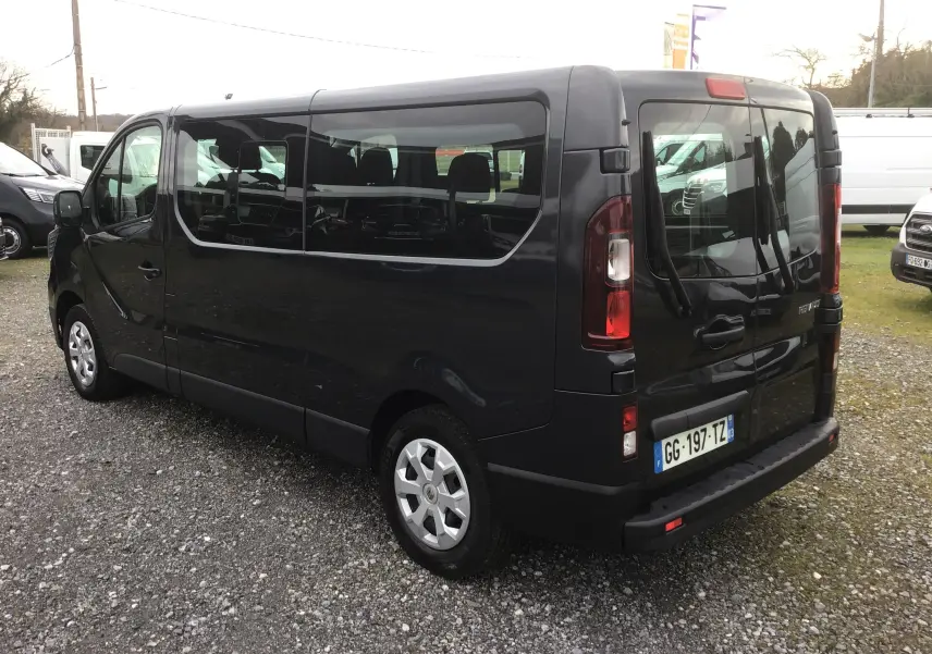 Vue 3/4 arrière droite d’un Renault Trafic Combi gris comète avec vitres latérales et hayon double.