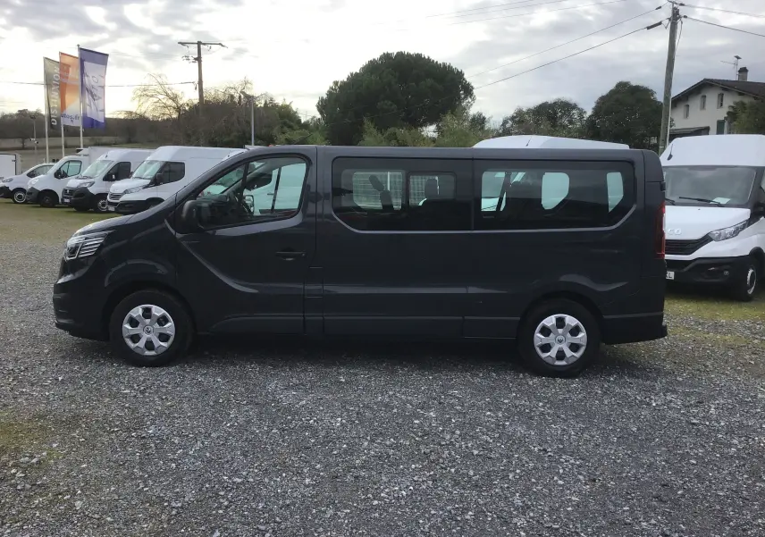 Vue de profil côté gauche d’un Renault Trafic Combi gris comète 2022, grand fourgon 9 places avec vitres latérales teintées.