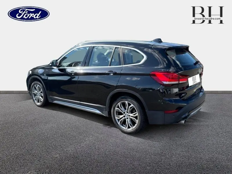 BMW X1 xDrive25e saphirschwarz vue 3/4 arrière droit, jantes alu et feux arrière LED visibles.