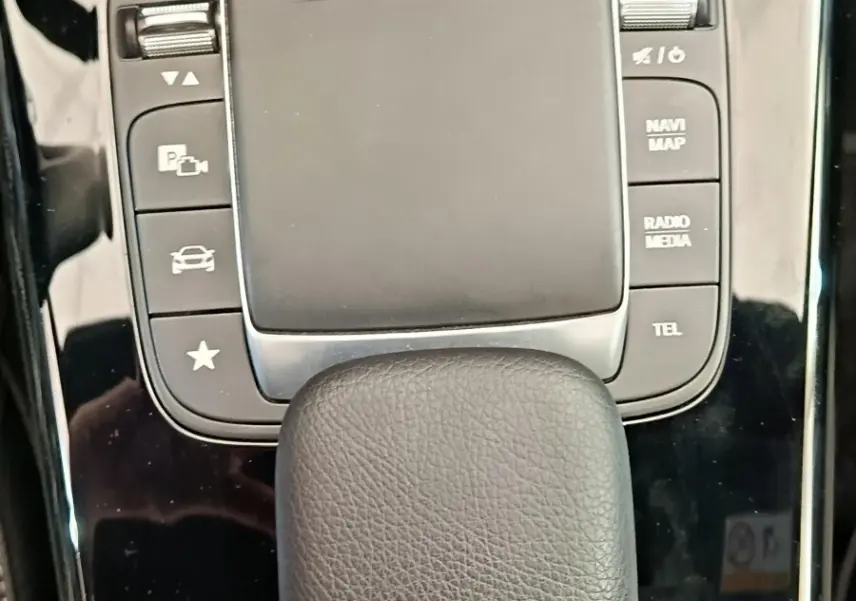 Vue rapprochée du pavé tactile noir et des boutons de commande sur la console centrale brillante d'une Mercedes Classe A blanche.