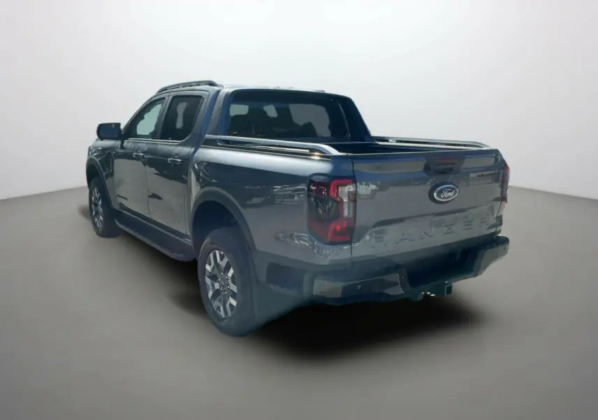 Ford Ranger 2.3 PHEV gris carbone vu 3/4 arrière droit avec benne et barres de toit visibles.