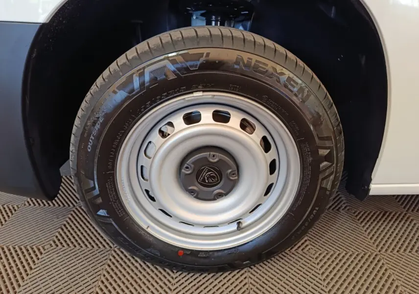 Gros plan sur la roue avant droite d’un Peugeot Partner blanc, avec jante acier et pneu Nexen visible.