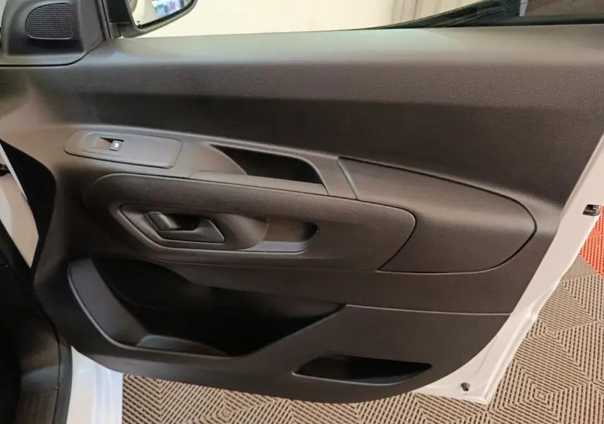 Vue rapprochée de la porte côté conducteur noire du Peugeot Partner blanc, avec poignée et commande de vitre électrique.