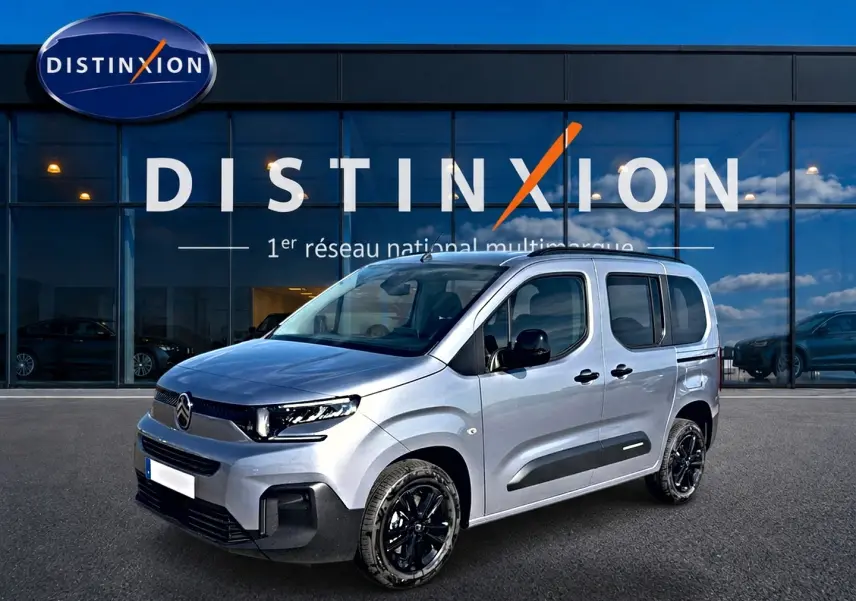 Vue 3/4 avant droite d'un Citroën Berlingo 2026 gris acier avec jantes noires et protections latérales noires.