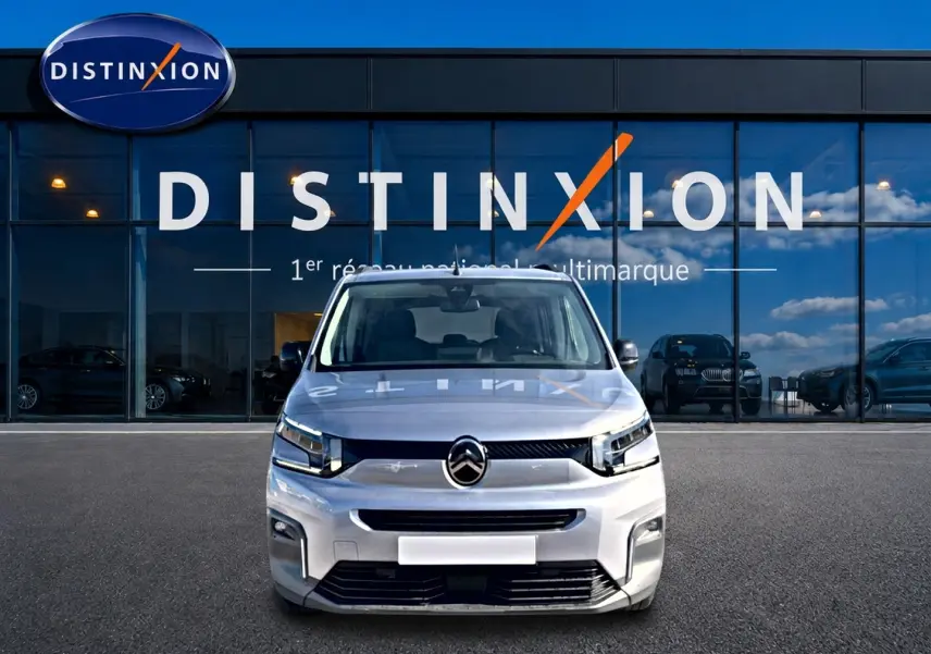 Vue avant d'un Citroën Berlingo 2026 gris acier, avec phares LED et calandre noire devant un showroom Distinxion.