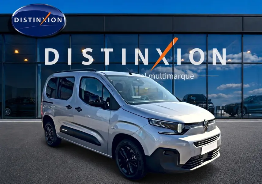 Vue 3/4 avant droite d'un Citroën Berlingo gris acier avec jantes noires devant un showroom Distinxion.