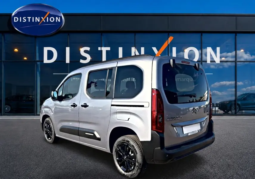 Vue 3/4 arrière droite du Citroën Berlingo N1 steel grey avec jantes noires devant un showroom Distinxion.